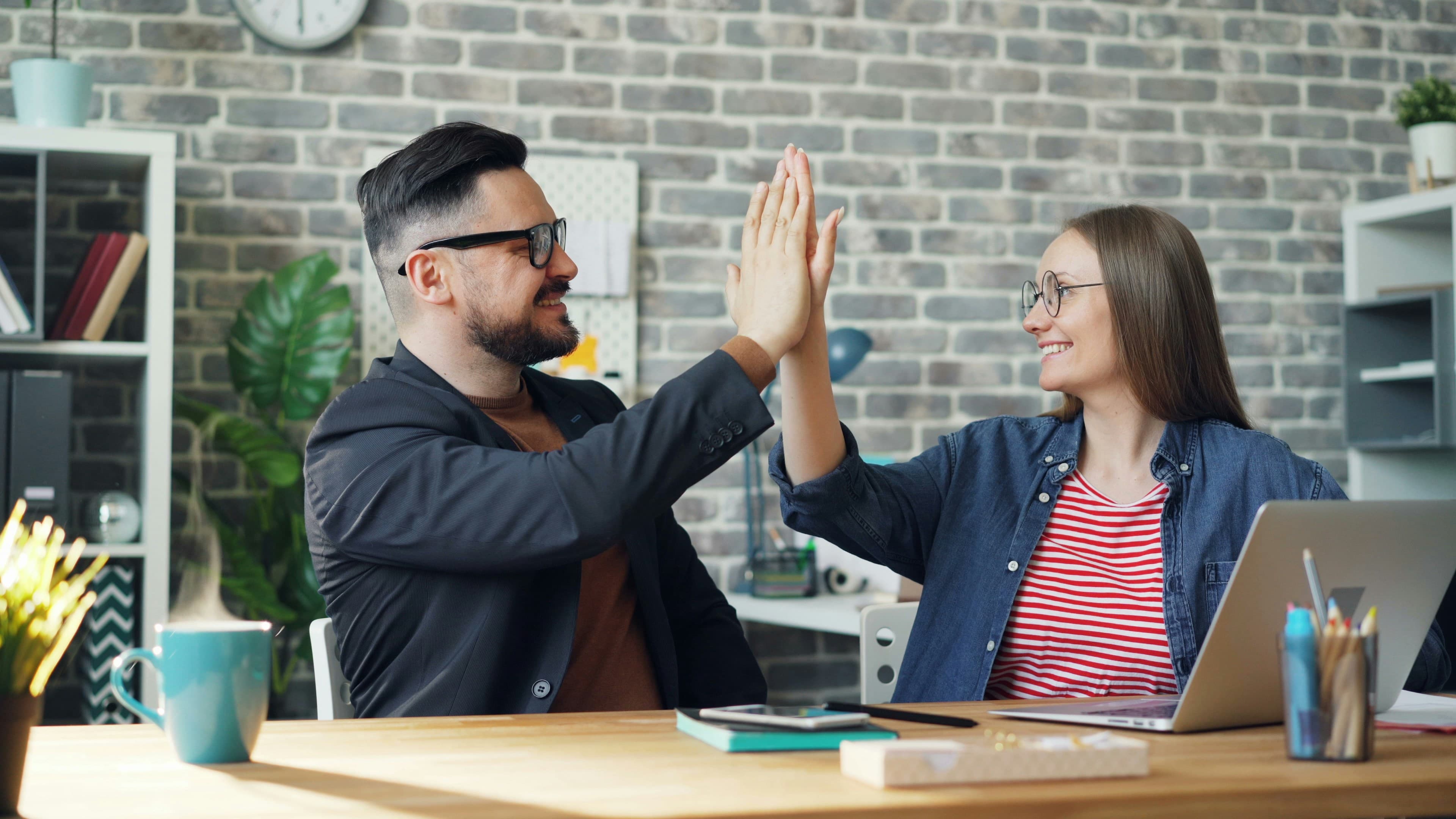 Collègues se félicitant avec un high-five au bureau
